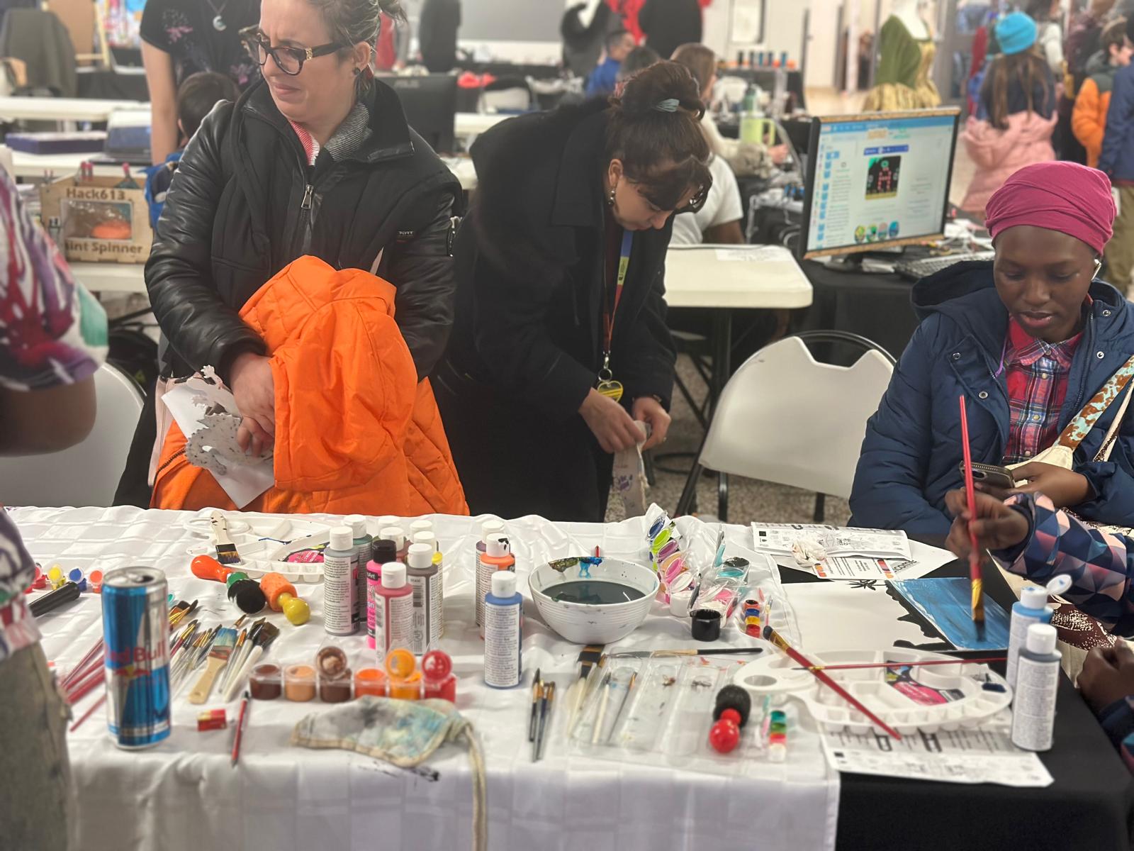 Community members painting and creating together at a workshop table.