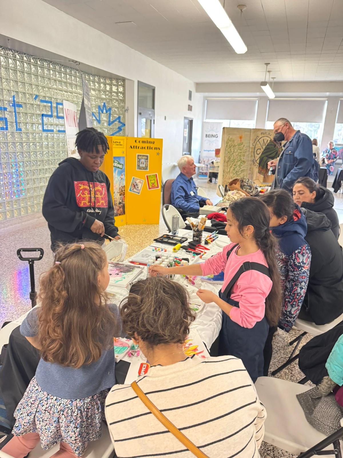 Youth leading a painting activity for children and families.